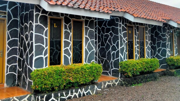 A building with a tiled roof, stone facade, and multiple windows. - Hotel Intan Niaga (Banjaran)