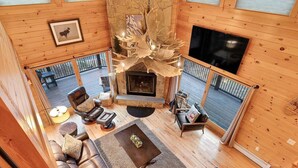 A spacious living room with a fireplace, leather furniture, and a large TV. - Mt Lodge | Sunday River Views | Hot Tub | Game Room (Newry)