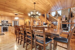 A spacious wooden interior with a dining area, kitchen, and staircase.