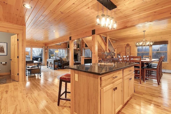 A spacious kitchen with wooden cabinets, a central island, and a dining area with wooden chairs.