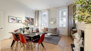Una sala de estar moderna con chimenea, una zona de comedor con mesa y sillas, y un sofá.