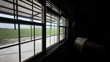 Een kamer met grote ramen en uitzicht op een groen veld.