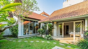 Una casa moderna con techo de tejas, piscina y un jardín bien cuidado con piedras a los lados.