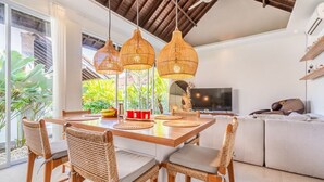 Un comedor moderno con una mesa de madera, sillas de mimbre y tres lámparas colgantes de mimbre.