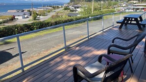 A deck with wicker chairs and a table, overlooking a residential area and a body of water.