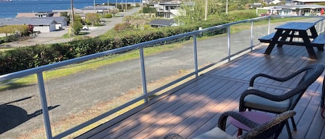 A deck with wicker chairs and a table, overlooking a residential area and a body of water.