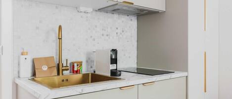 A modern kitchen with a stainless steel sink, white cabinets, and a marble backsplash.