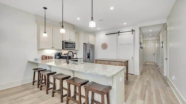 A modern kitchen with a large island, bar stools, and pendant lighting. - Beautifully furnished condo on Jekyll Riverfront! (Jekyll Island)