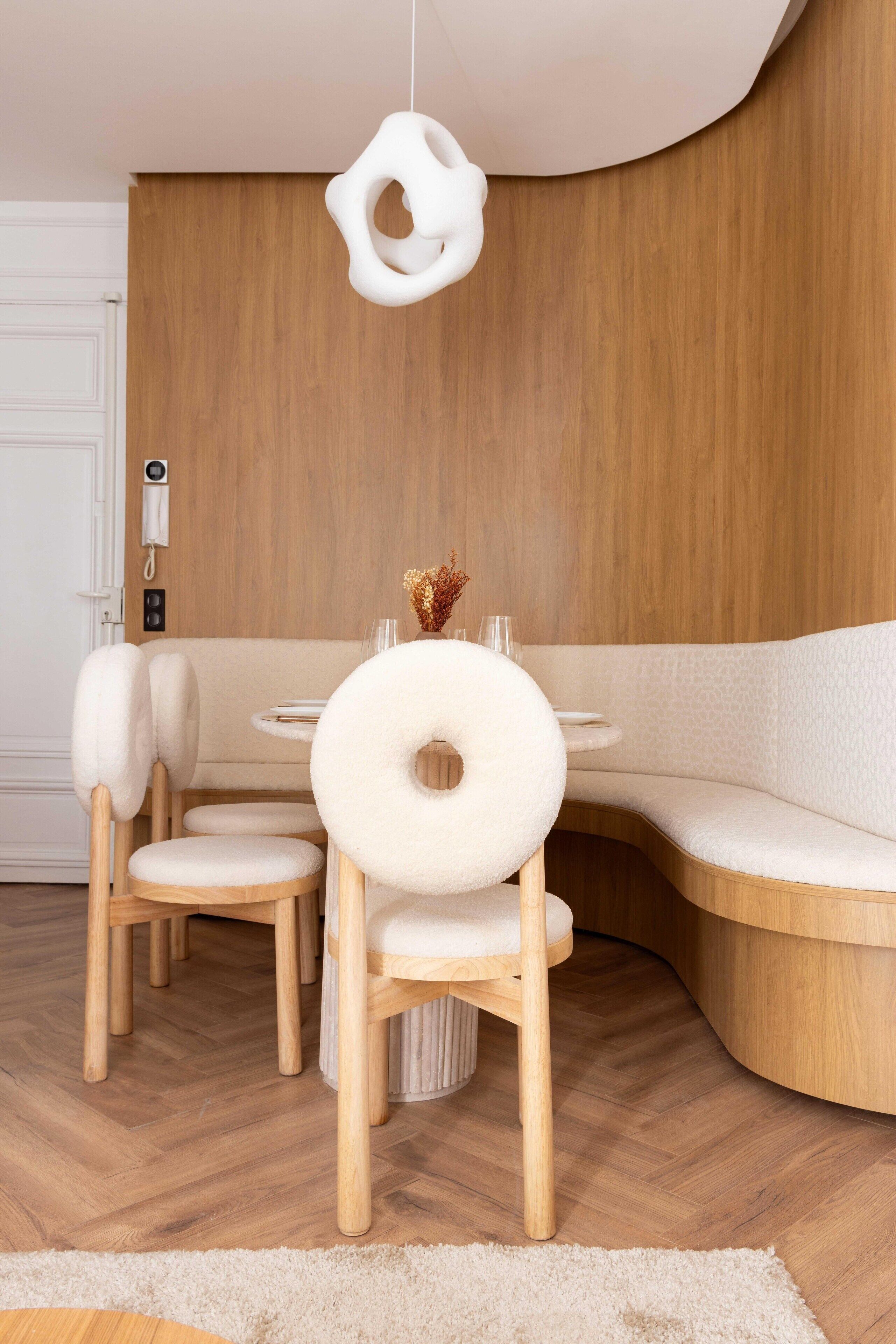 Un comedor moderno con una mesa redonda, sillas acolchadas y un banco empotrado.