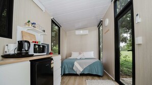 Una habitación compacta con cama, kitchenette y ventanas amplias.