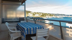 A balcony with a table and chairs, overlooking a marina with boats and buildings. - Location d'un studio cabine pour 4 personnes face mer, centre ville. (LE LAVANDOU)