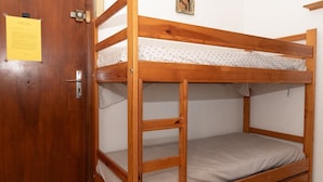 A bunk bed with a wooden frame, a door with a lock, and a small picture on the wall. - Location d'un studio cabine pour 4 personnes face mer, centre ville. (LE LAVANDOU)