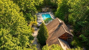Una vista aerea di una baita con piscina, circondata da alberi fitti.