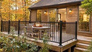 A wooden cabin with a deck, outdoor seating, and a glass door leading to the interior. - Private Pool & Hot tub! Minutes to Sebago Lake! Nature! Perfect all year-round. (Windham)