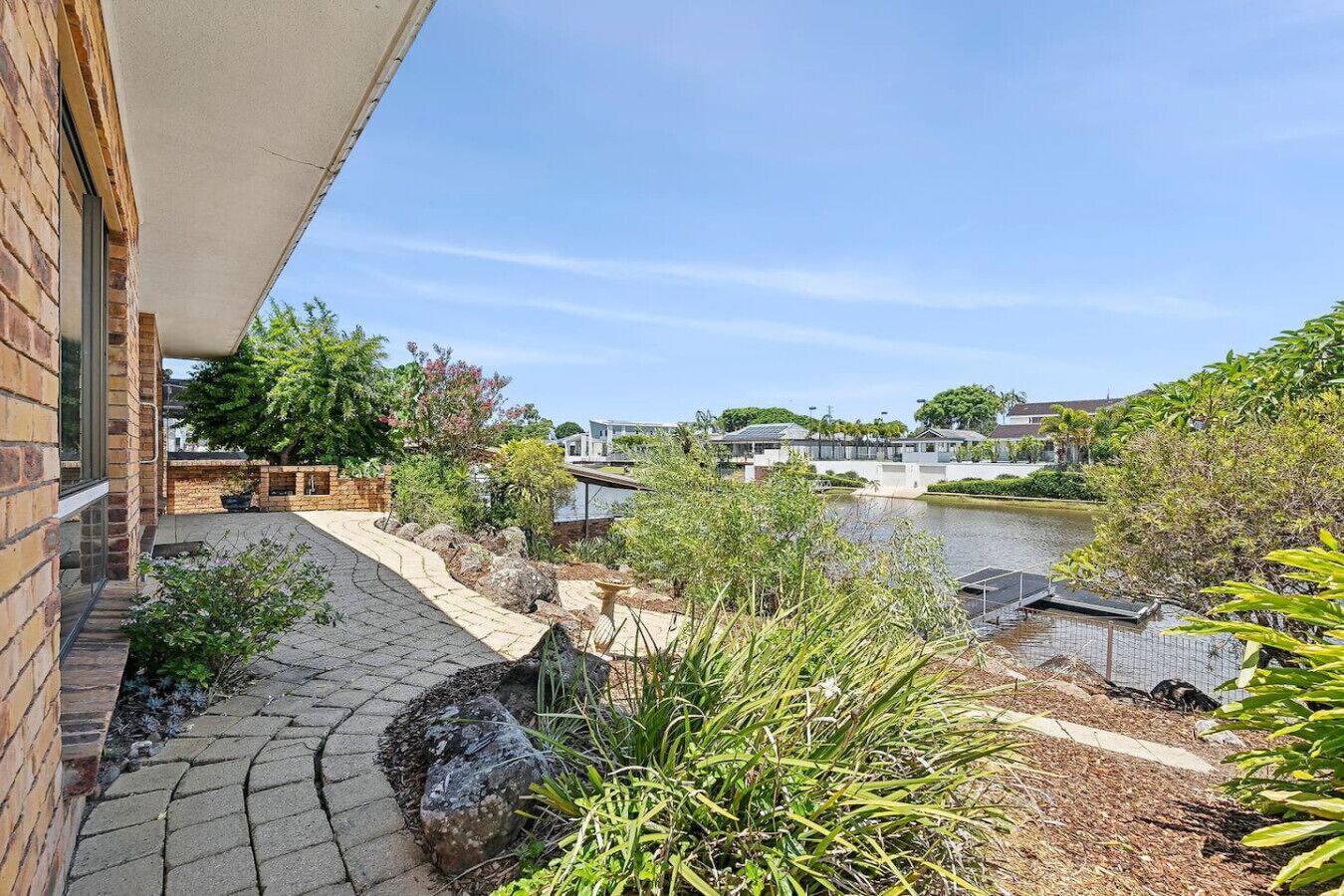 A courtyard with a paved walkway, a small pond, and surrounding greenery.