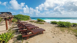 Een strand met houten ligbedden en een rieten hut.