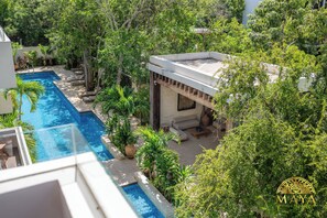 A rooftop pool area with a view of the surrounding greenery and a building with a covered seating area. - NHOA 303A Lux 2BR Pool View Aldea Zama (Tulum)