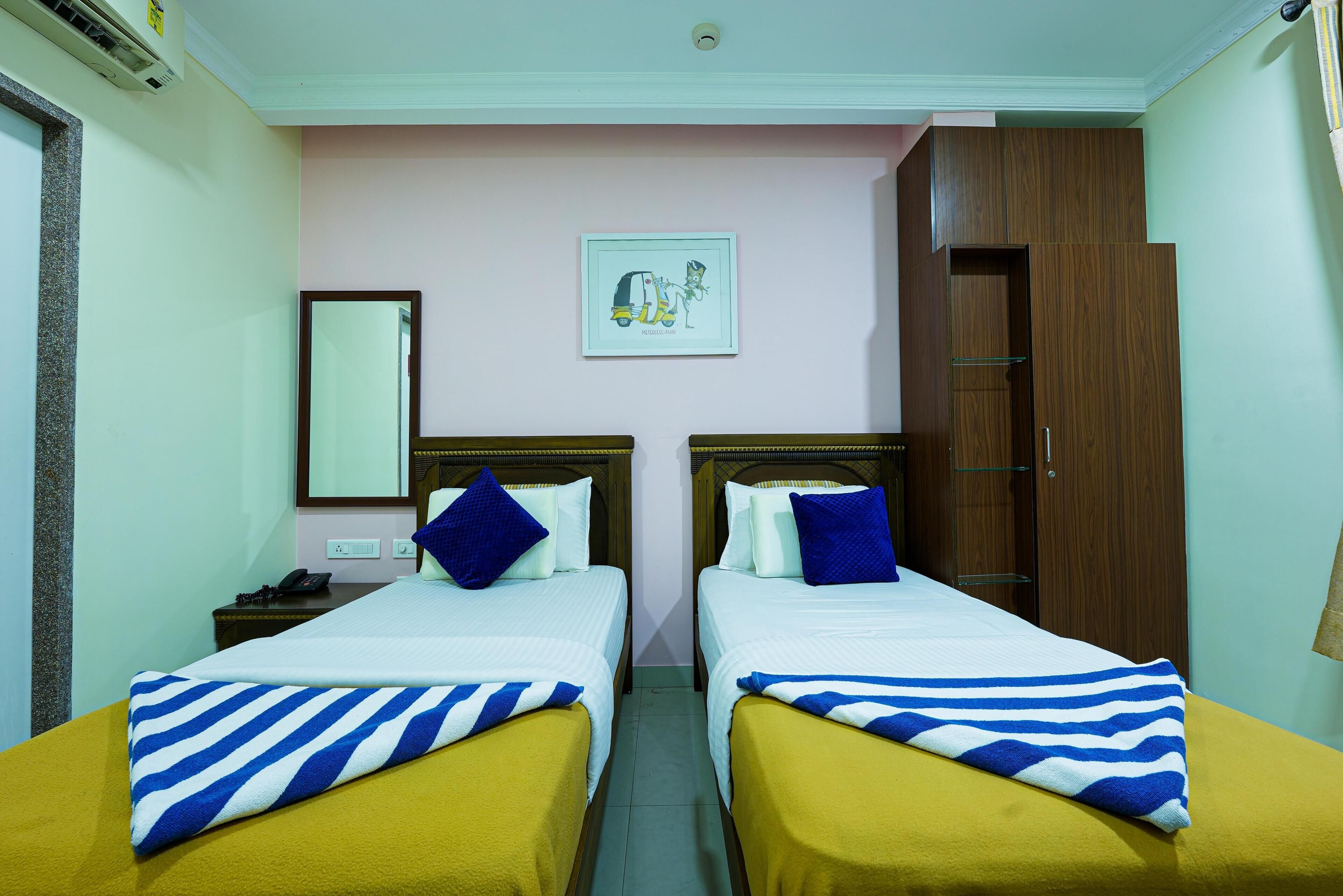 A hotel room with two beds, each with a striped blanket, a nightstand with a phone, and a framed picture on the wall.