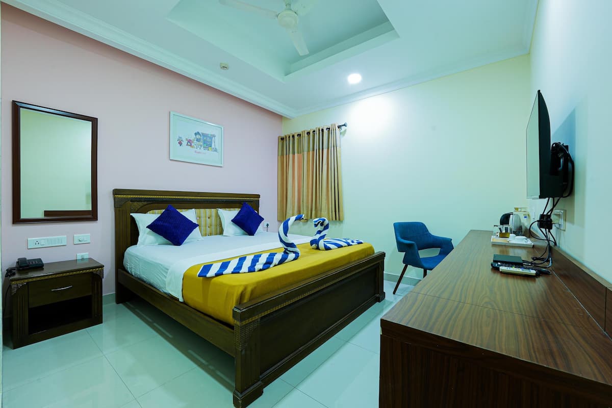 A hotel room with a bed, bedside table, chair, desk, and television.