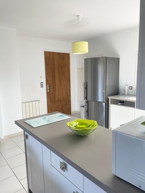 Enjoy cooking in this well-equipped kitchen with a stainless steel refrigerator, dishwasher, and grey countertop.