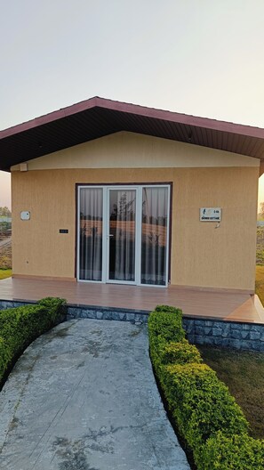 A small building with a flat roof, a sliding glass door, and a sign indicating it is a 'DRONGO COTTAGE'.