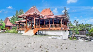 A traditional pavilion with a tiled roof, a wooden balcony, and a paved courtyard.