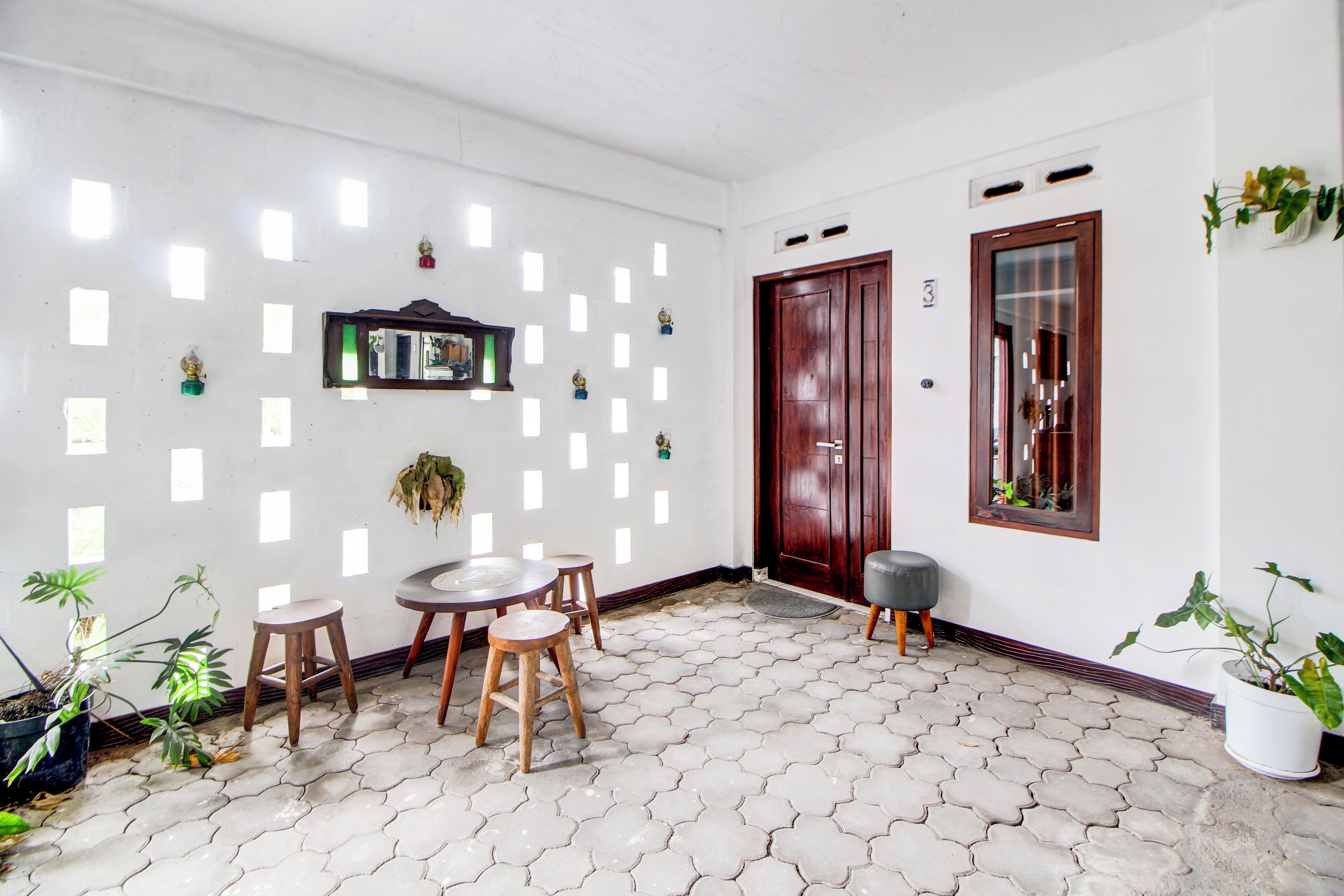 A room with a tiled floor, a wooden table with stools, a bookshelf, and a door.