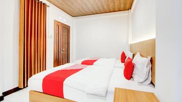 Una habitación de hotel moderna con cabecera de madera, una cama grande con ropa blanca y roja, y una puerta de madera.