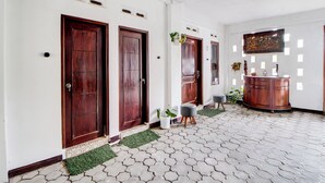 A hallway with three wooden doors, a potted plant, a small table, and a cabinet.