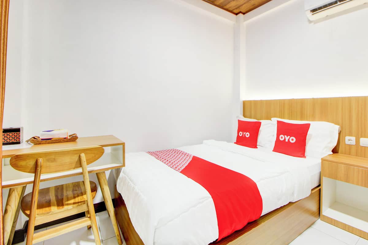 Une chambre d’hôtel bien rangée, avec un lit, un bureau et une chaise.