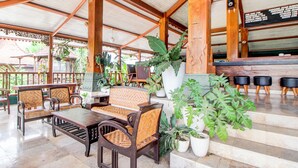 A covered outdoor seating area with wooden furniture and potted plants.