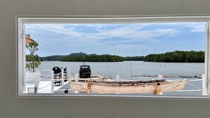 A wooden boat docked at a pier with a clear view of a calm lake and distant hills.