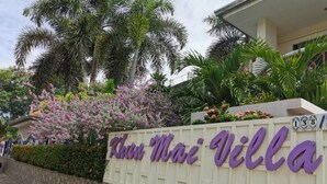 A sign for Khatu Mai Villa with a stone wall and lush greenery. - khun mai villa (Pattaya)