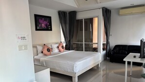 A modern hotel room with a bed, a black leather sofa, a TV, and a desk. - khun mai villa (Pattaya)