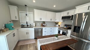 Una cocina moderna con armarios blancos, electrodomésticos de acero inoxidable y una mesa de comedor de madera.