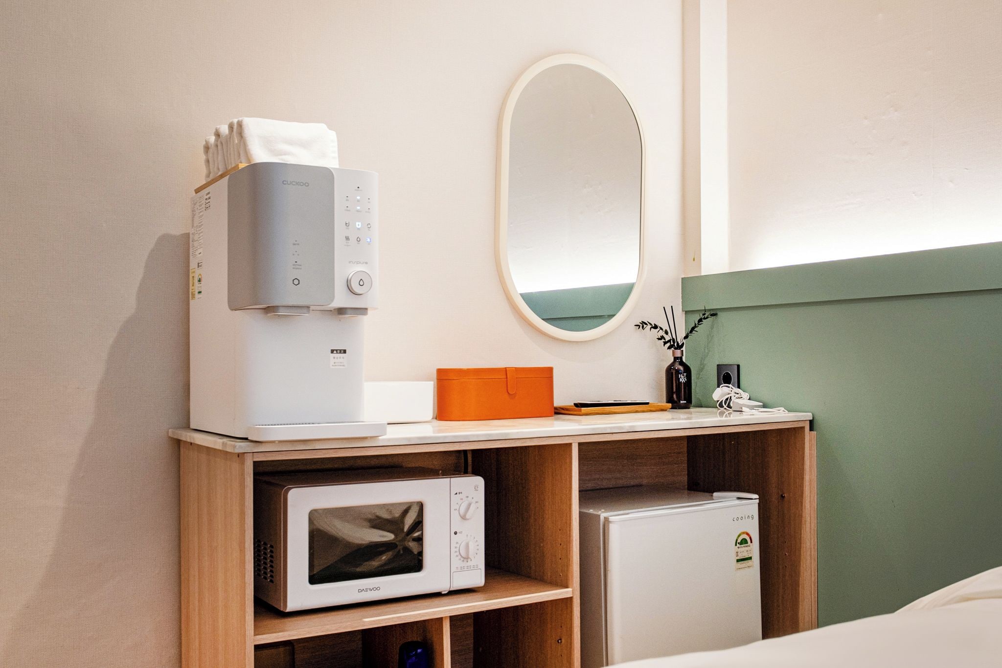 A hotel room with a minibar, a microwave, a coffee machine, a mirror, and a small refrigerator.