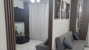 A living room with a grey sofa, a small table with a plant, and a TV mounted on the wall. - Nice apartment in Cercado de Lima (Callao)