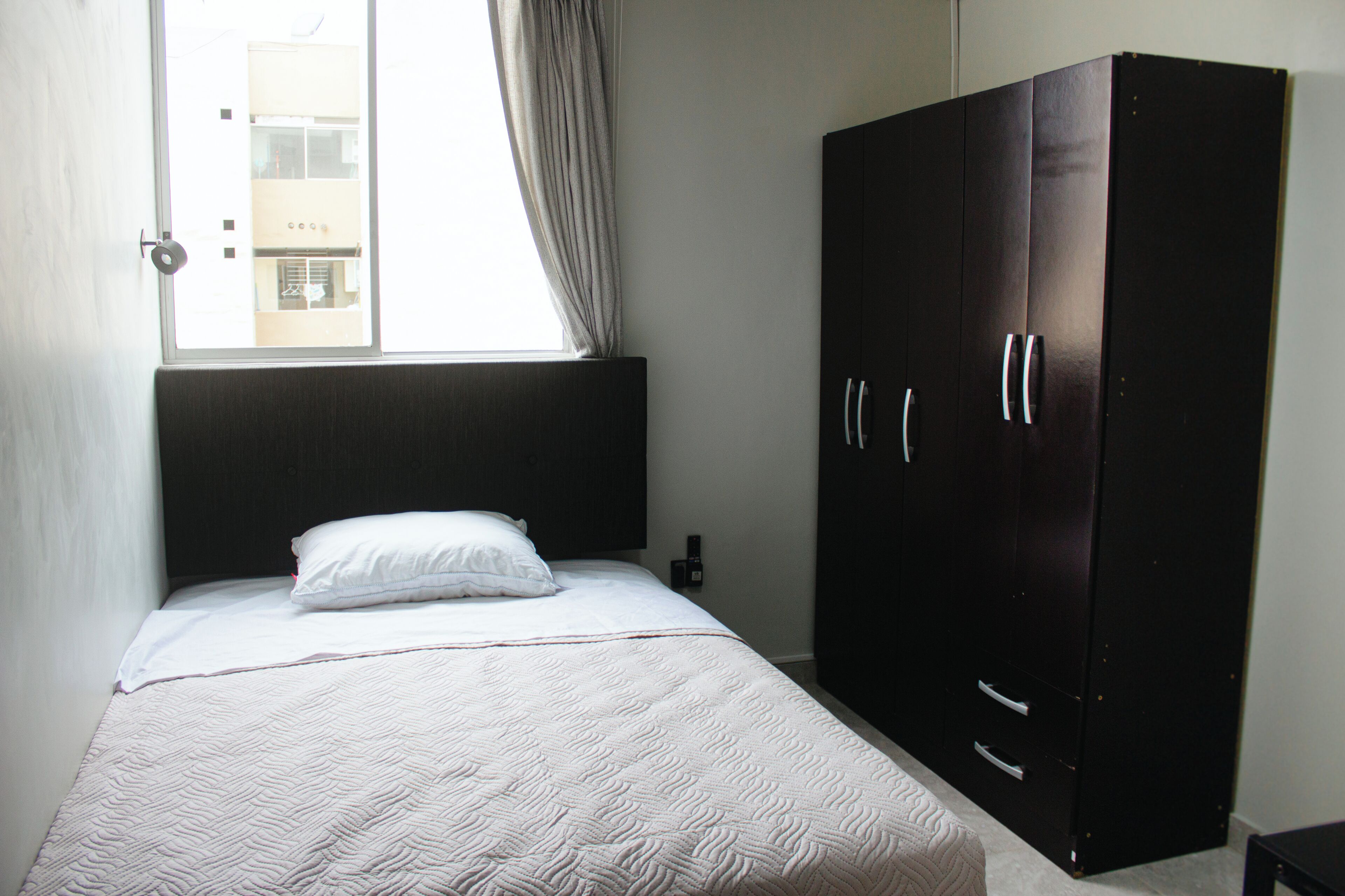 Ein Schlafzimmer mit einem Bett, einem Kleiderschrank und einem Fenster mit Vorhängen.