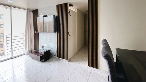 A modern hotel room with a glass partition, a flat-screen TV, a small table, and a chair. - Nice apartment in Cercado de Lima (Callao)