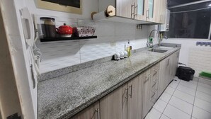 A kitchen with white tiled backsplash, granite countertop, wooden cabinets, and a built-in oven. - Nice apartment in Cercado de Lima (Callao)