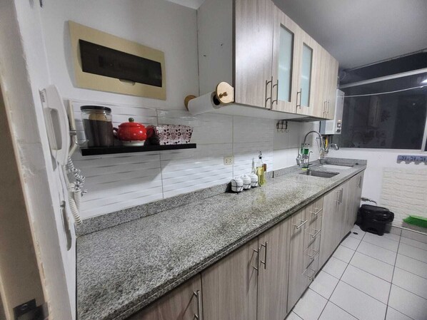 A kitchen with white tiled backsplash, granite countertop, wooden cabinets, and a built-in oven.