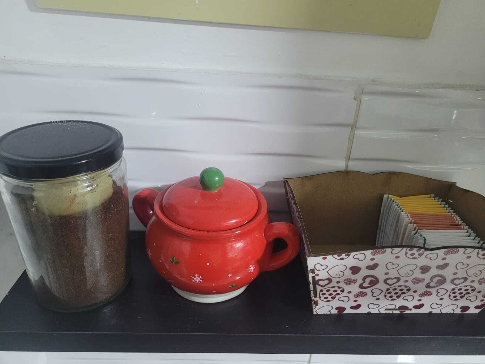 A kitchen counter with a red teapot, a glass jar, and a box of tea bags.