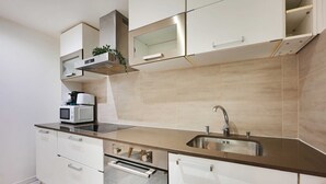 A modern kitchen with white cabinets, a stainless steel sink, and a microwave.