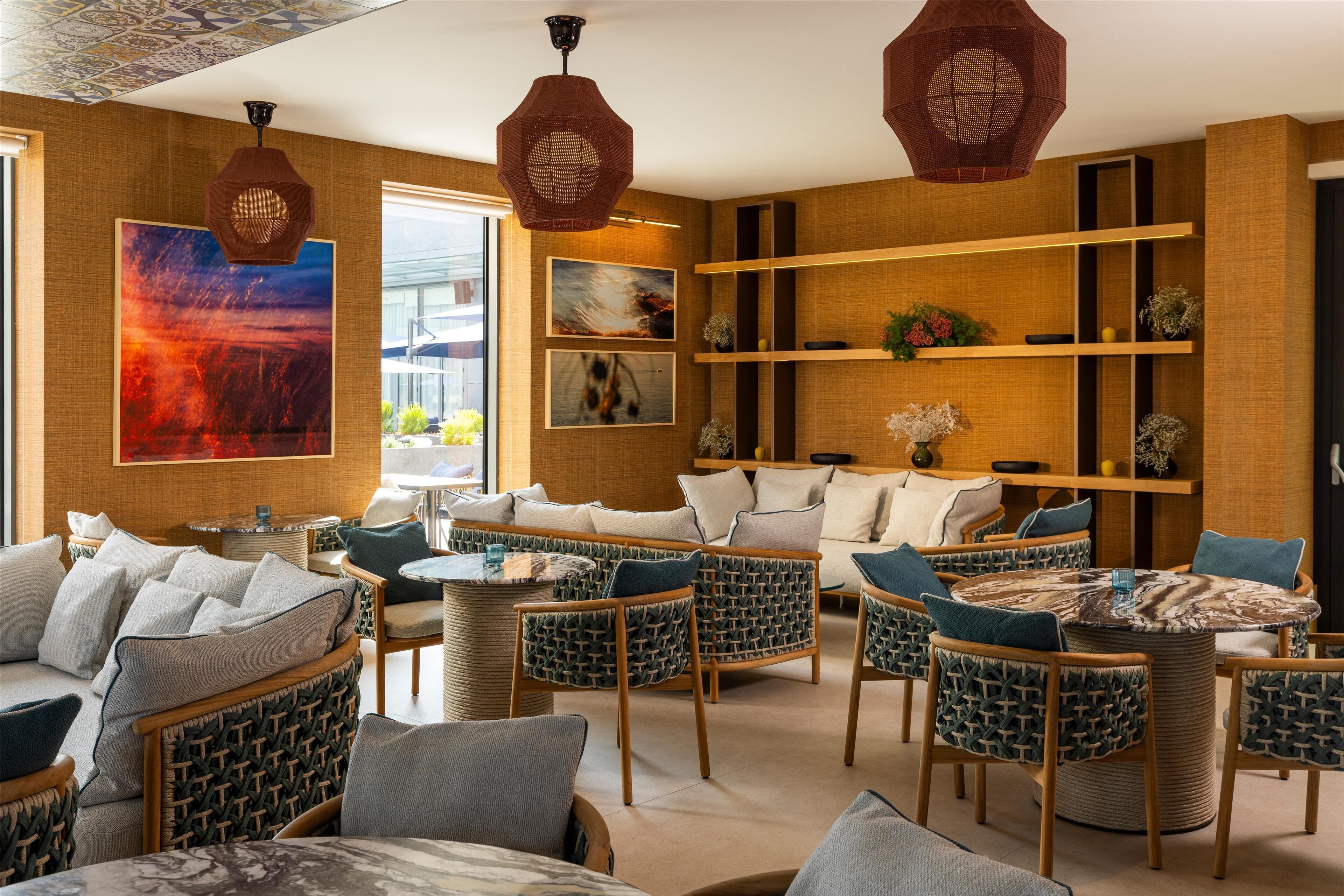 A modern lounge area with wicker furniture, a large abstract painting, and wooden shelves with decorative items.