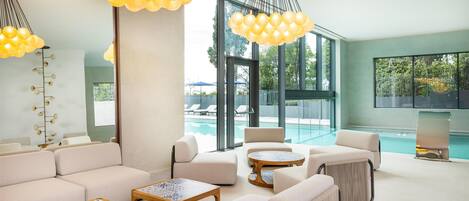 A modern lounge area with sofas, round tables, and hanging spherical light fixtures.