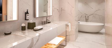 A modern bathroom with a marble vanity, a freestanding bathtub, and a bench.