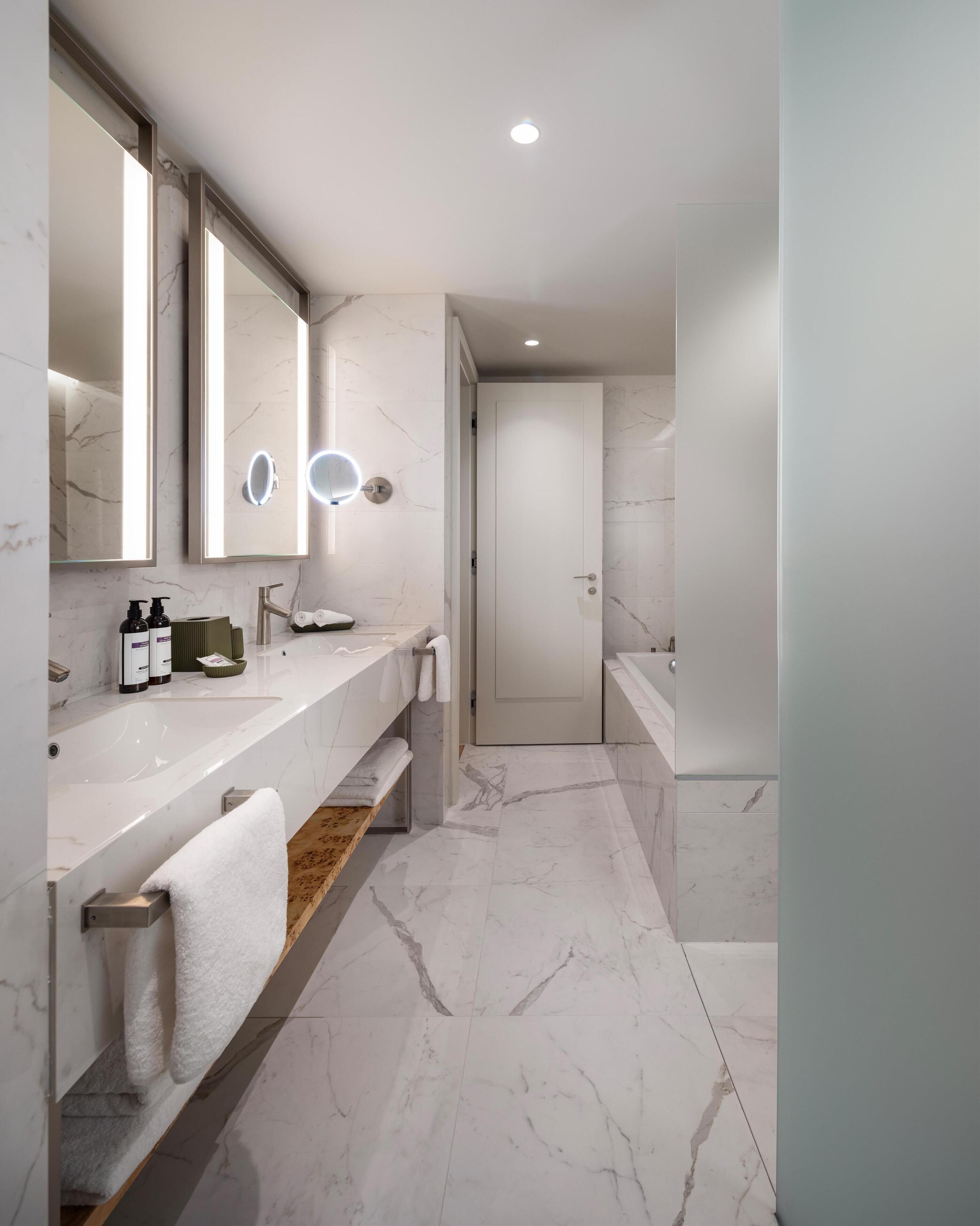 A modern bathroom with a marble countertop, a large mirror, and a built-in sink.