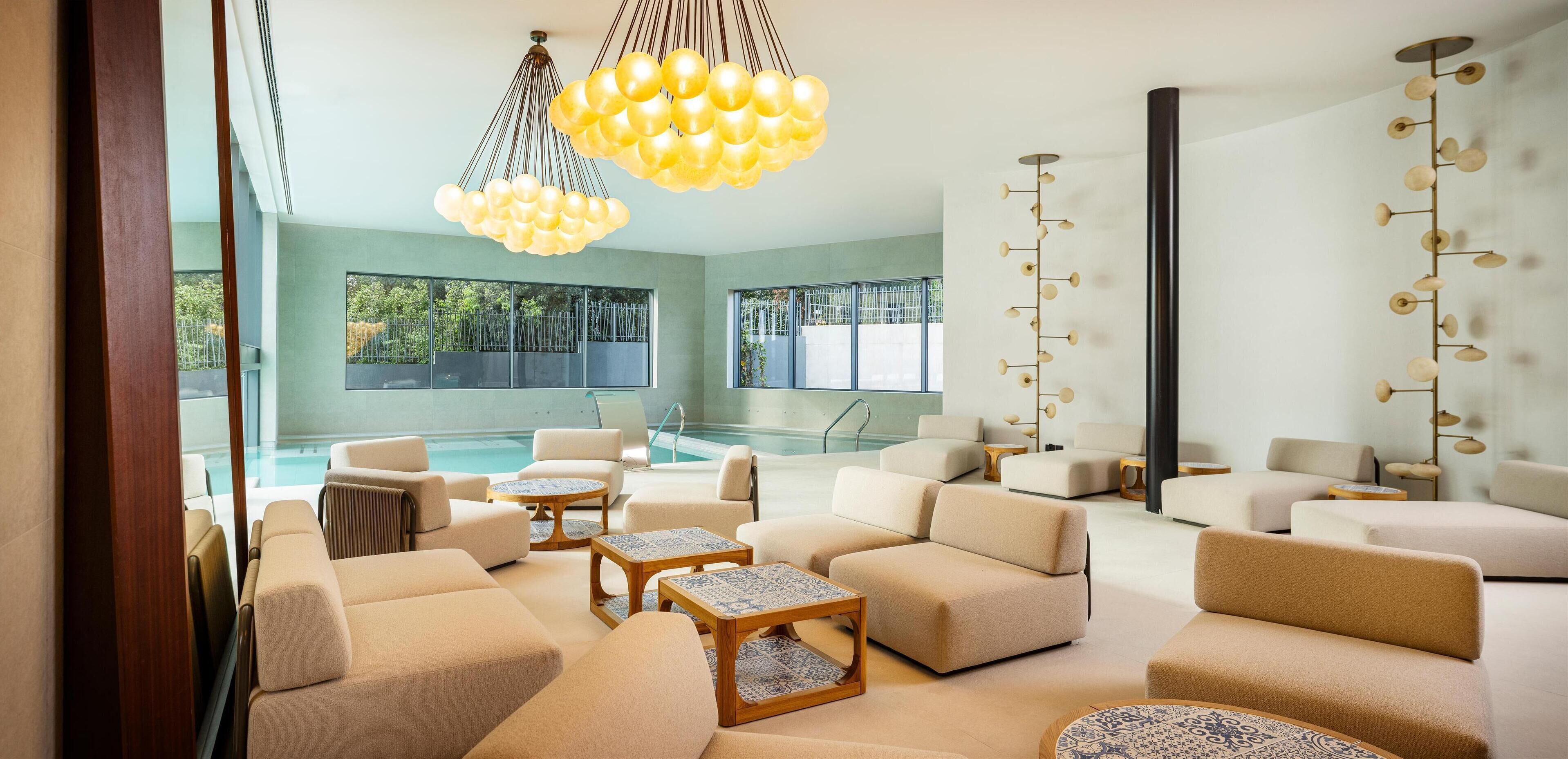 A modern lounge area with a pool, comfortable seating, and unique lighting fixtures.