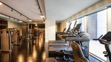A modern gym with treadmills, weight machines, and a large mirror.