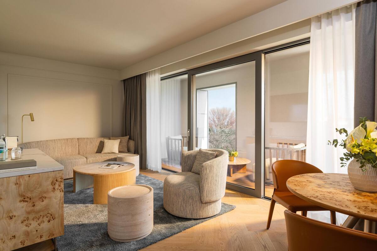A modern living room with a sofa, armchair, coffee table, and a dining table.